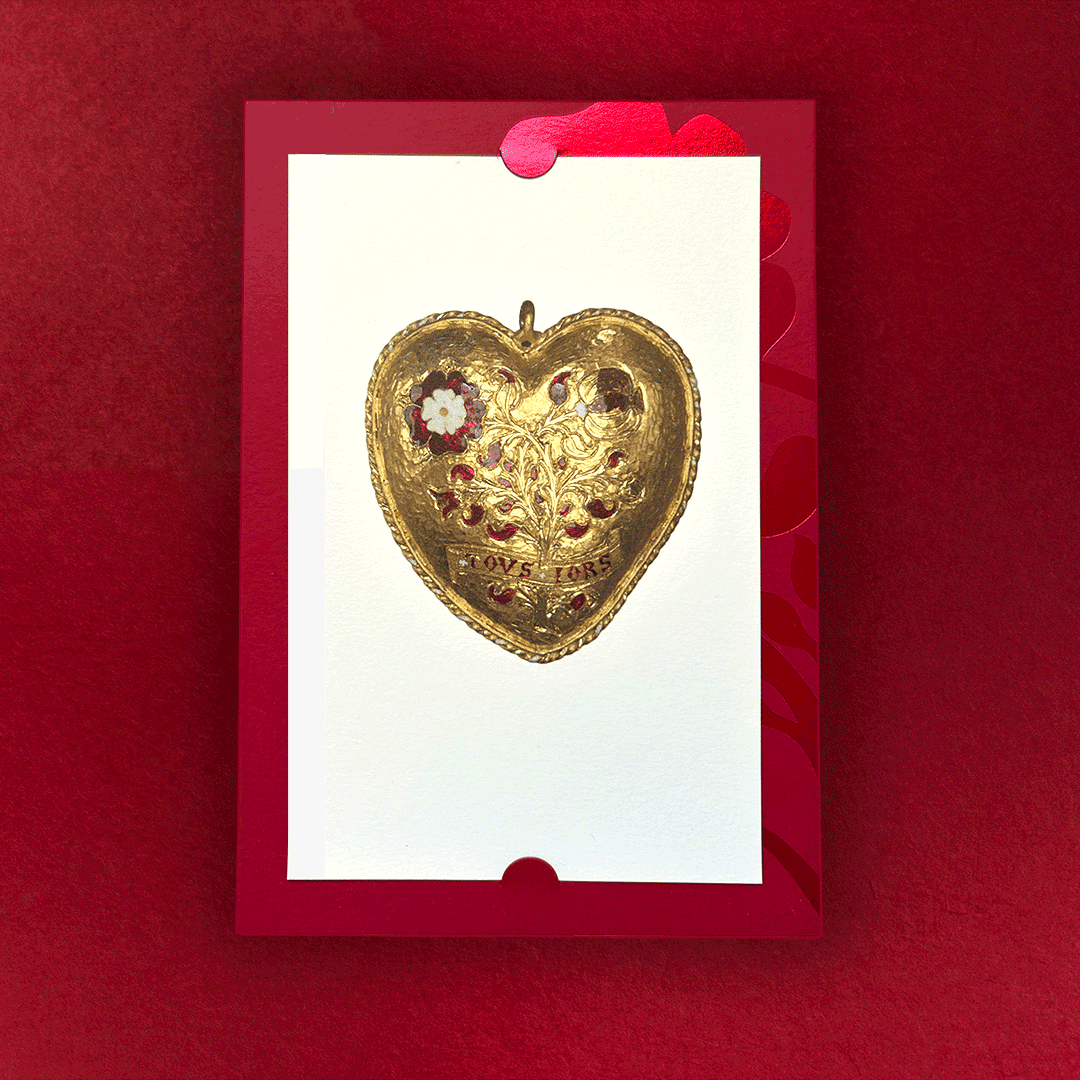 Gold Tudor Heart pendant on a cream postcard insert, held in its foiled red invitation sleeve.