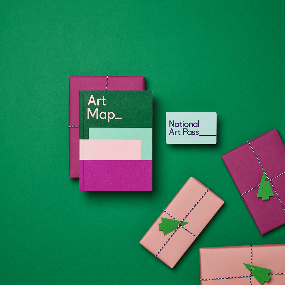 Art Map guidebook and National Art Pass card photographed on a green background with pink and magenta wrapped gifts tied with striped twine and green paper trees.